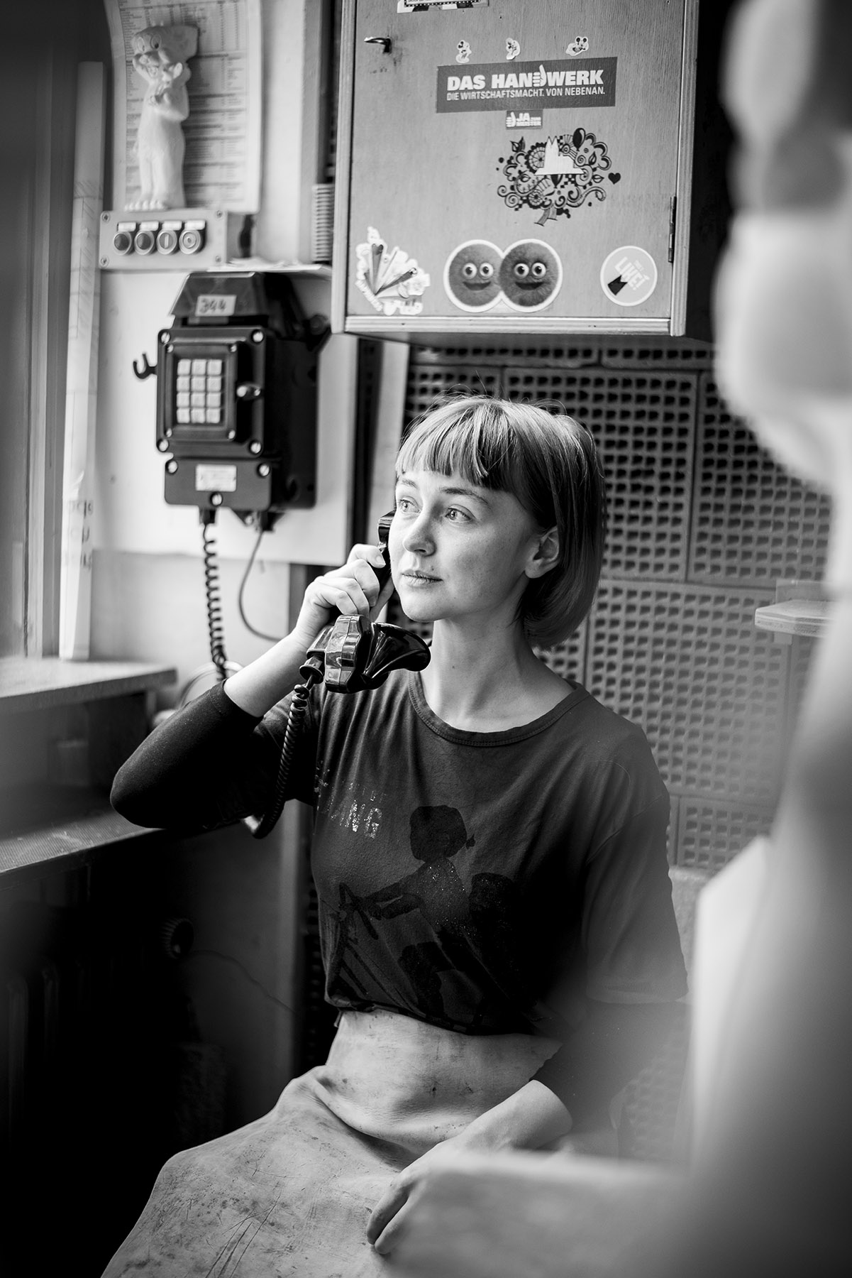 Schwarzweiß Portrait einer telefonierenden Frau in Werkstatt