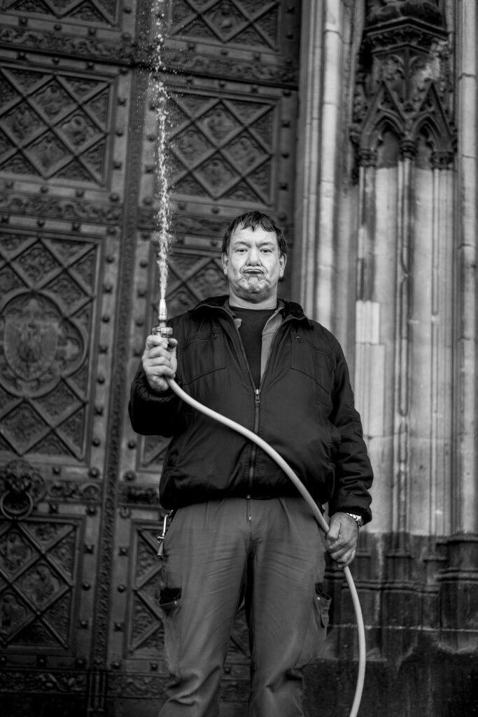 Arbeiter vor dem Kölner Dom mit einem Wasserschlauch in der Hand