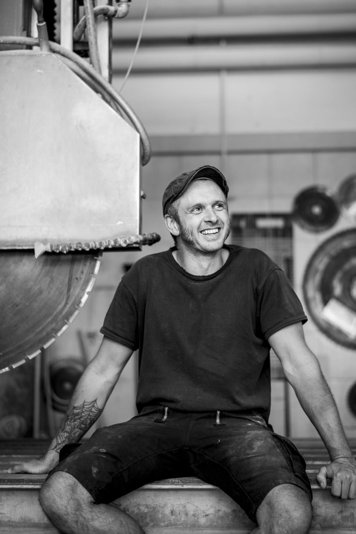 Steinmetz sitzt neben Maschine und lächelt