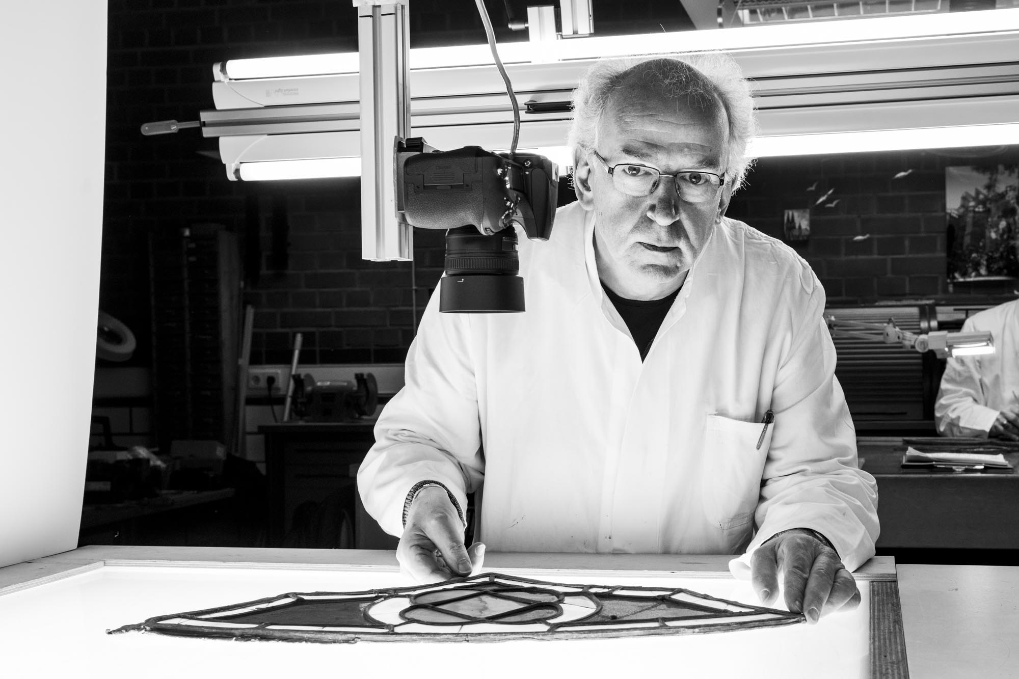 Schwarzweißportrait älterer Glasrestaurator am Leuchttisch