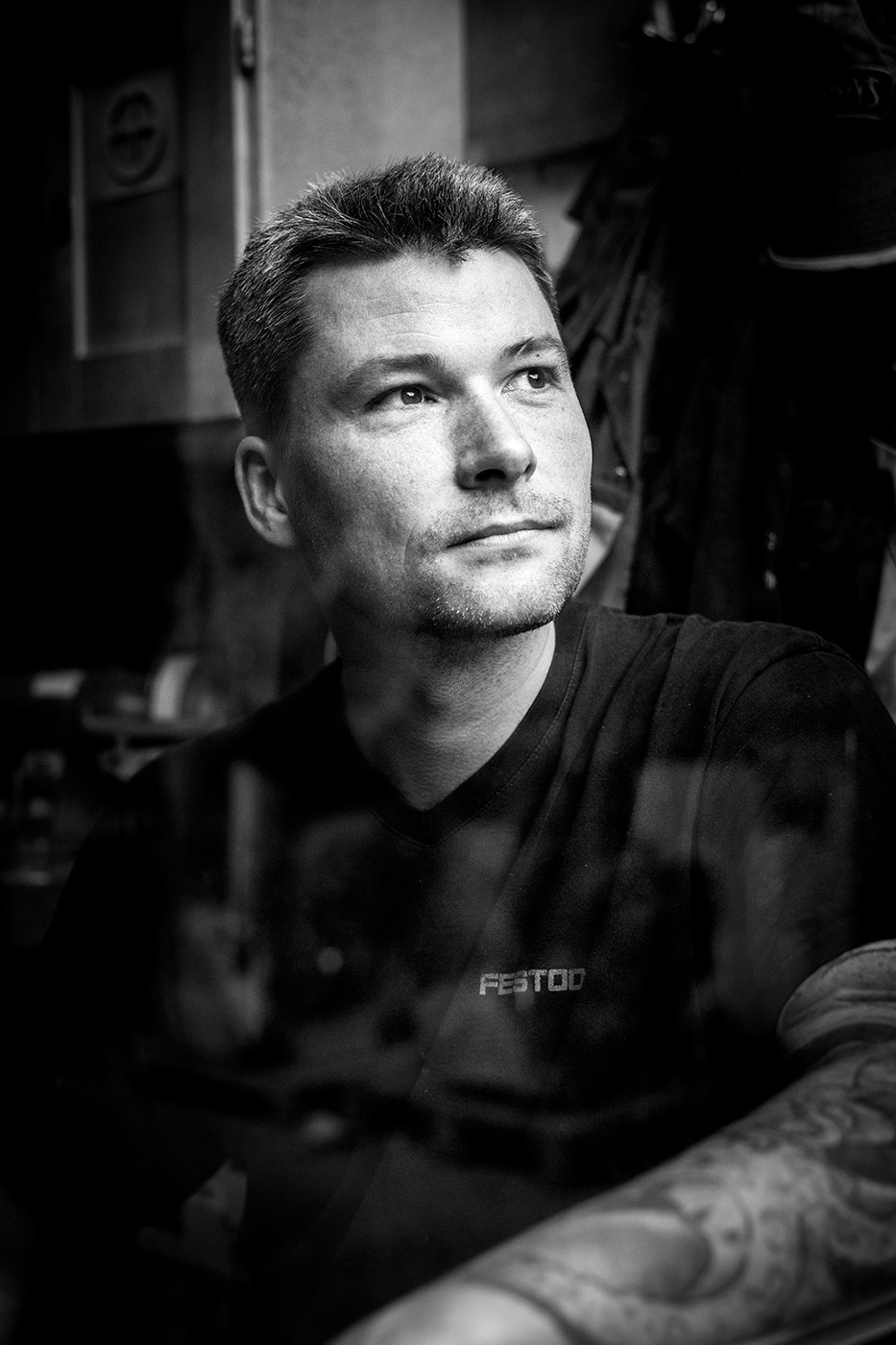 Schwarzweiß-Portrait eines Handwerkers durch eine Glasscheibe