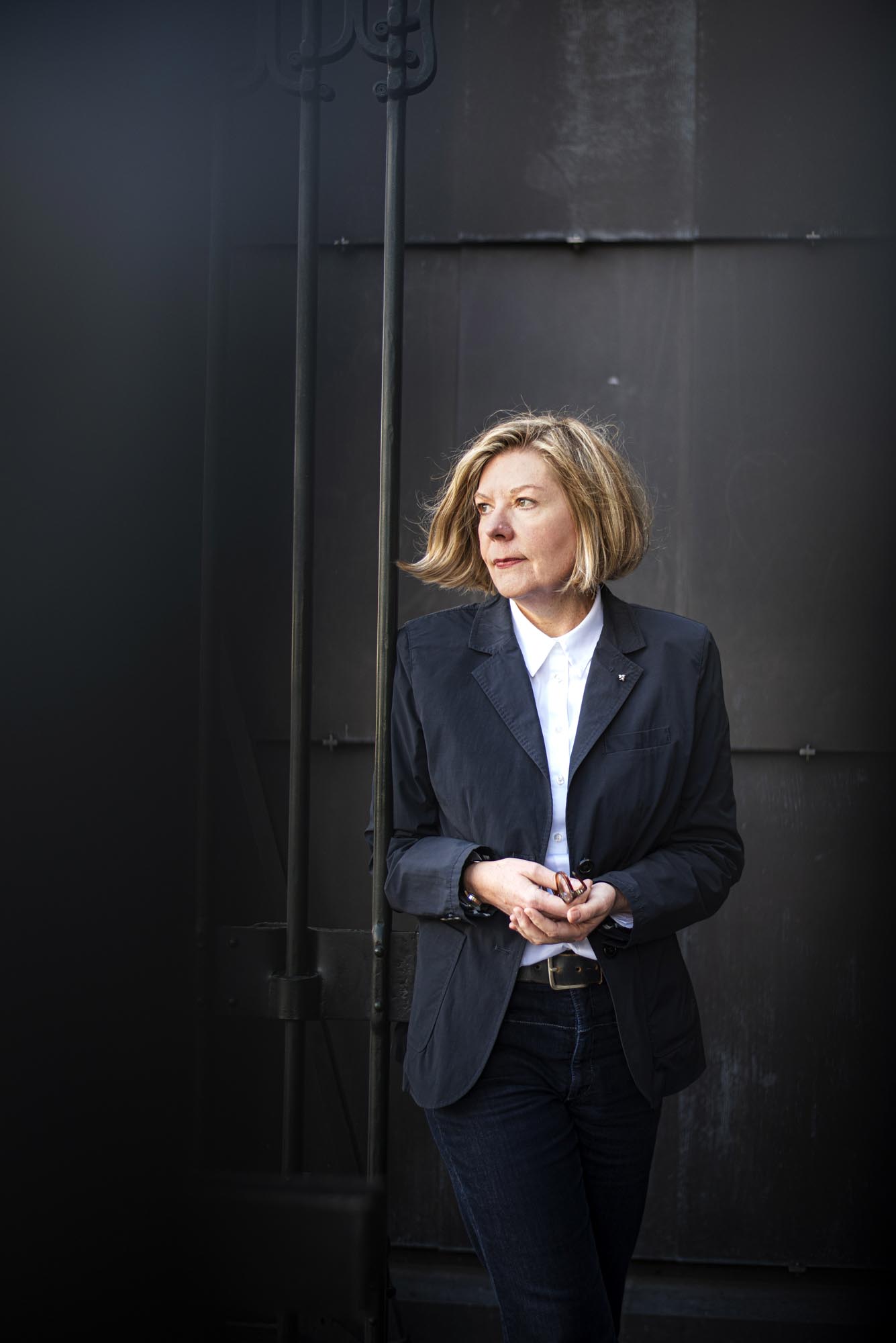 Portrait einer blonden Frau mit Jacket vor dunklem Hintergrund