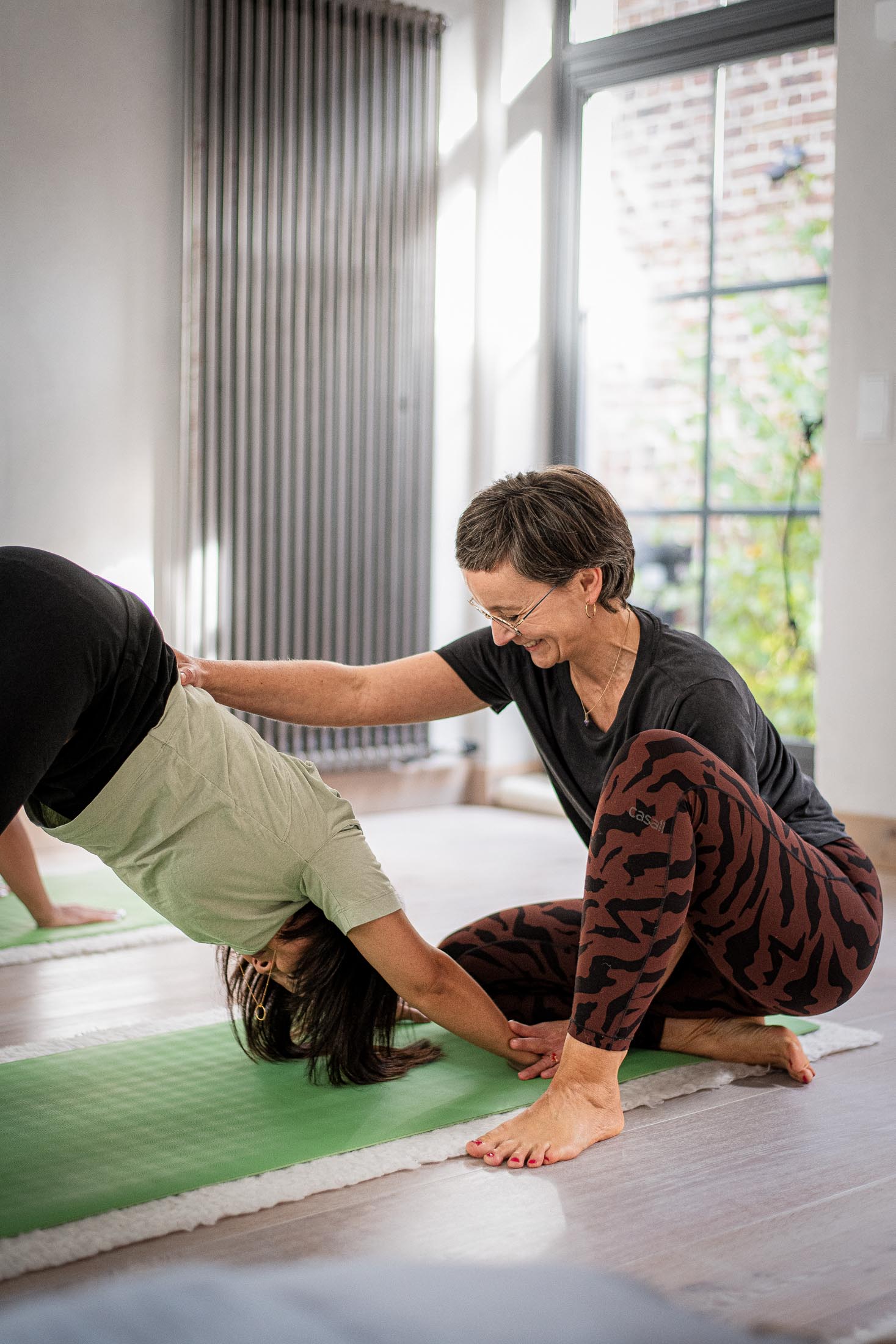 Yogalehrerin unterstützt Teilnehmerin in einer Bodenübung