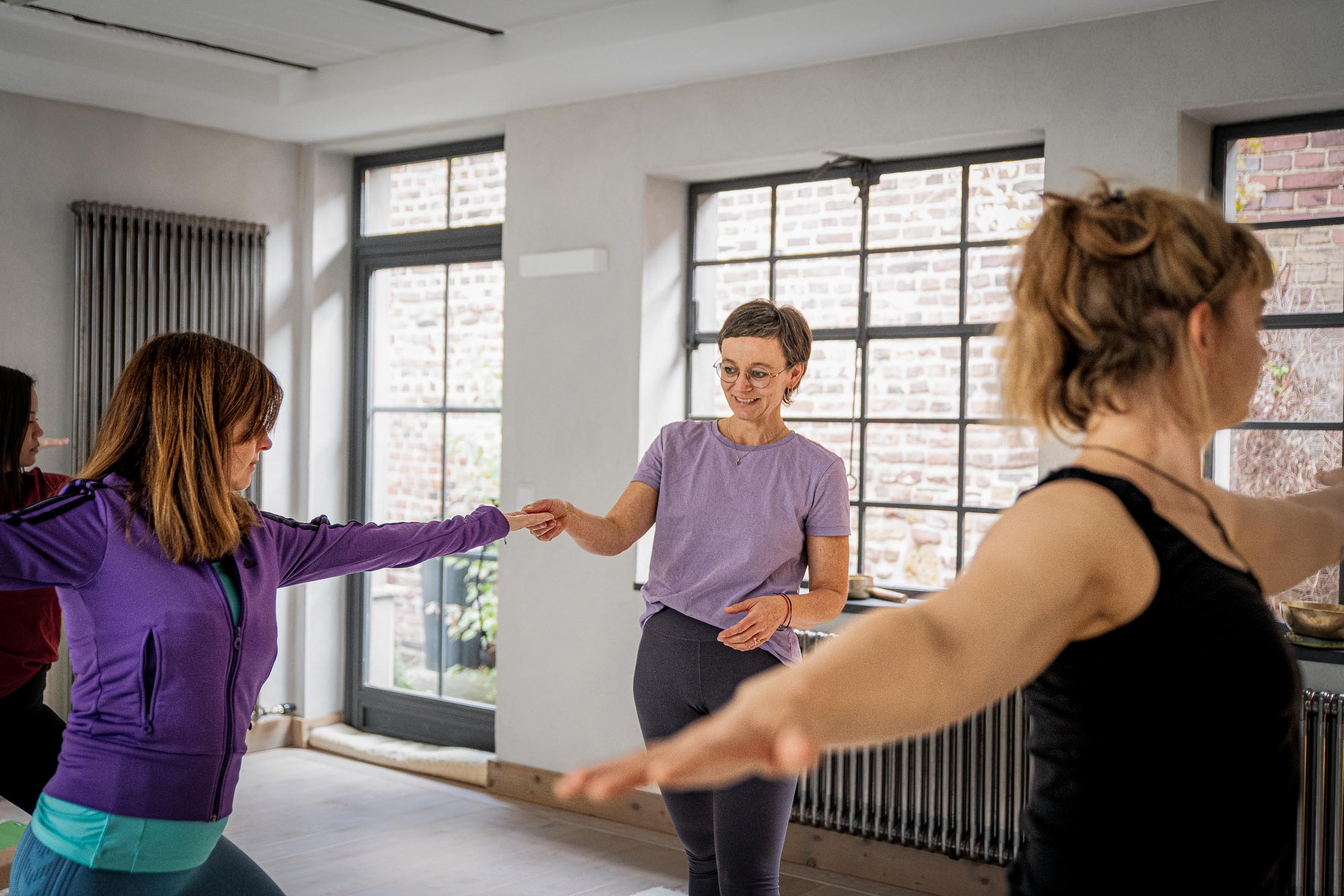 Yogalehrerin korrigiert Haltung einer Teilnehmerin im Stand