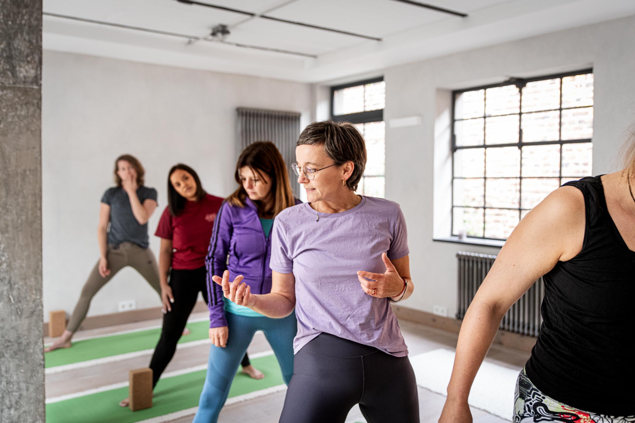 Yoga Gruppe übt gemeinsam im hellen Kursraum