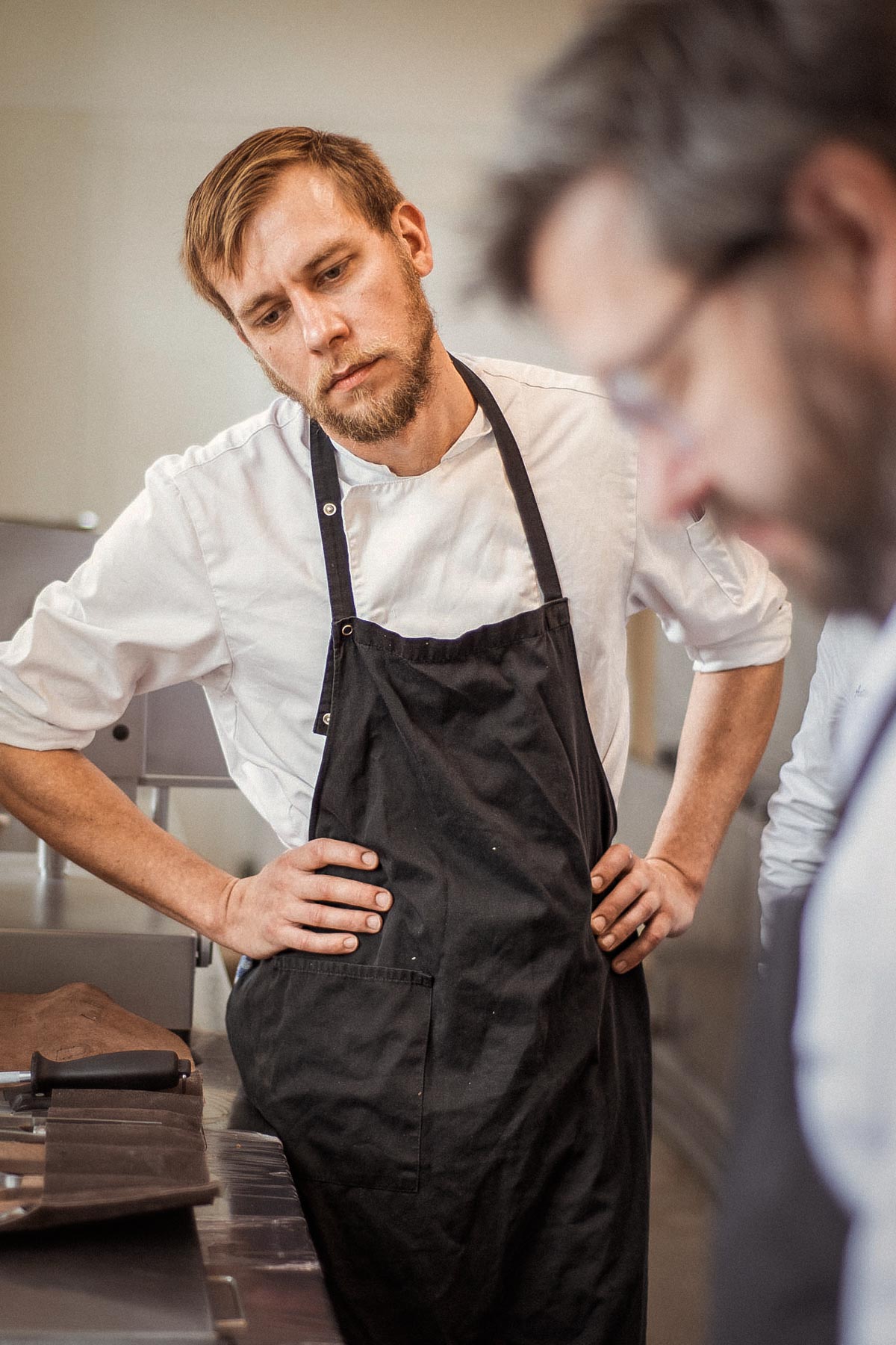 Lehrling schaut einem Koch bei der Arbeit über die Schulter
