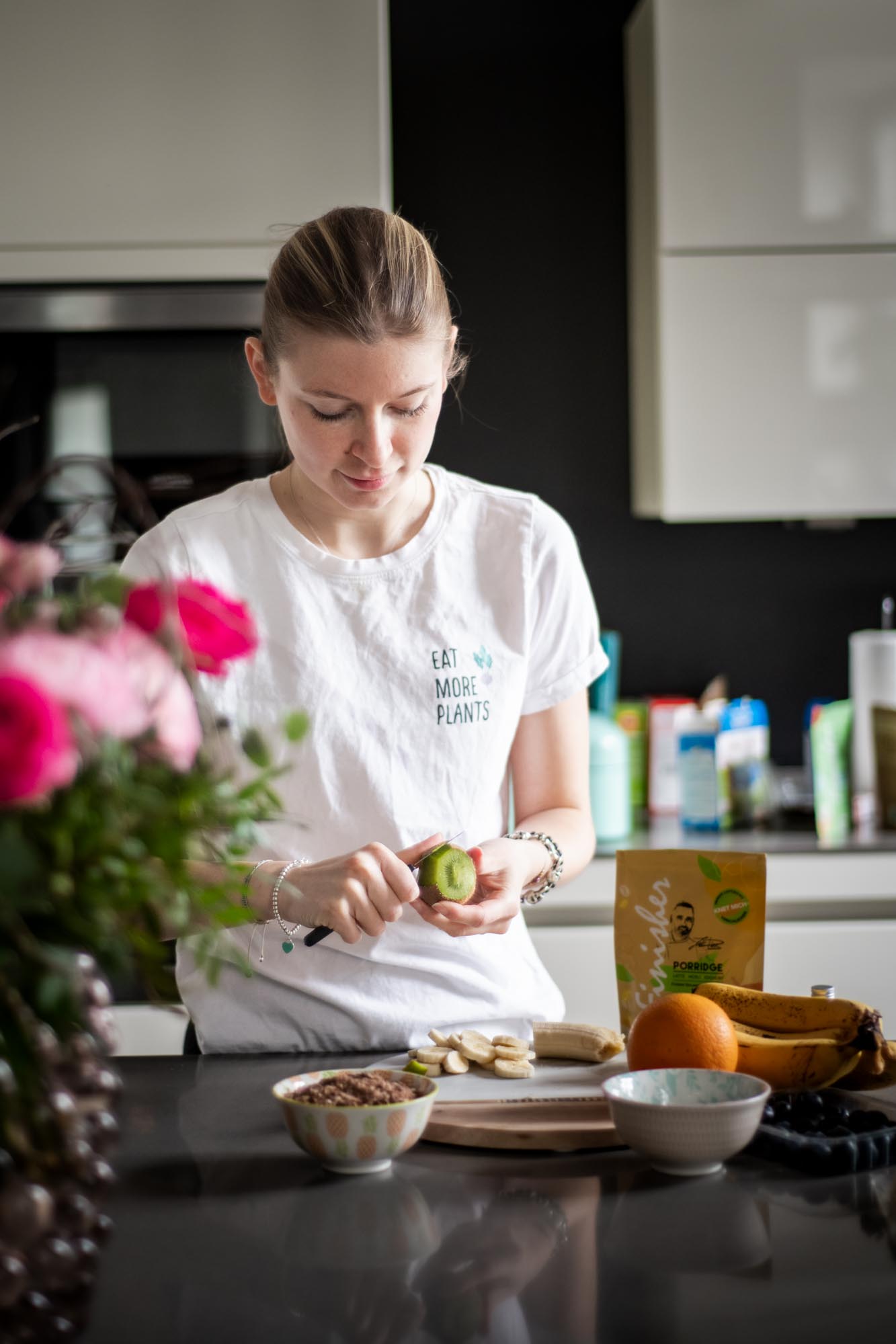 Frau schneidet Obst in der Küche, Produktverpackung im Hintergrund