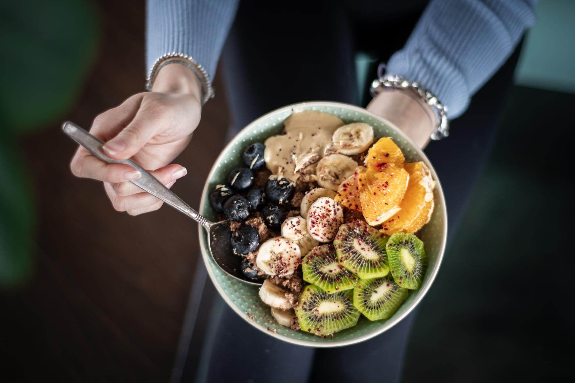 Hände halten Schale mit Bowl aus Müsli und Obst