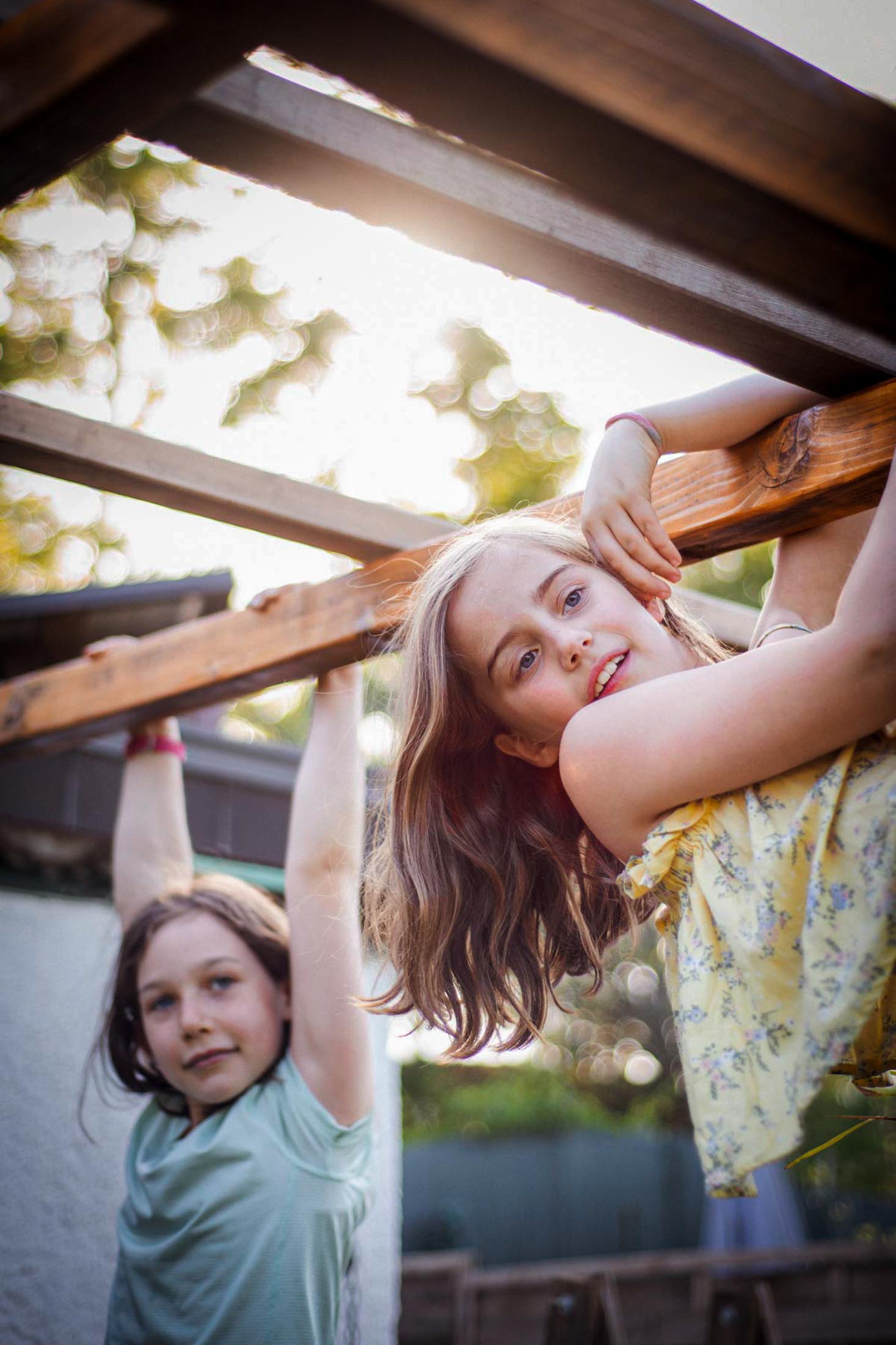 Zwei Kinder spielen an einer Holzkonstruktion im Garten