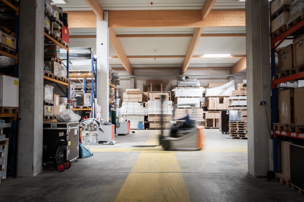 Breiter Blick durch Produktionshalle mit fahrendem Gabelstapler und Regalen