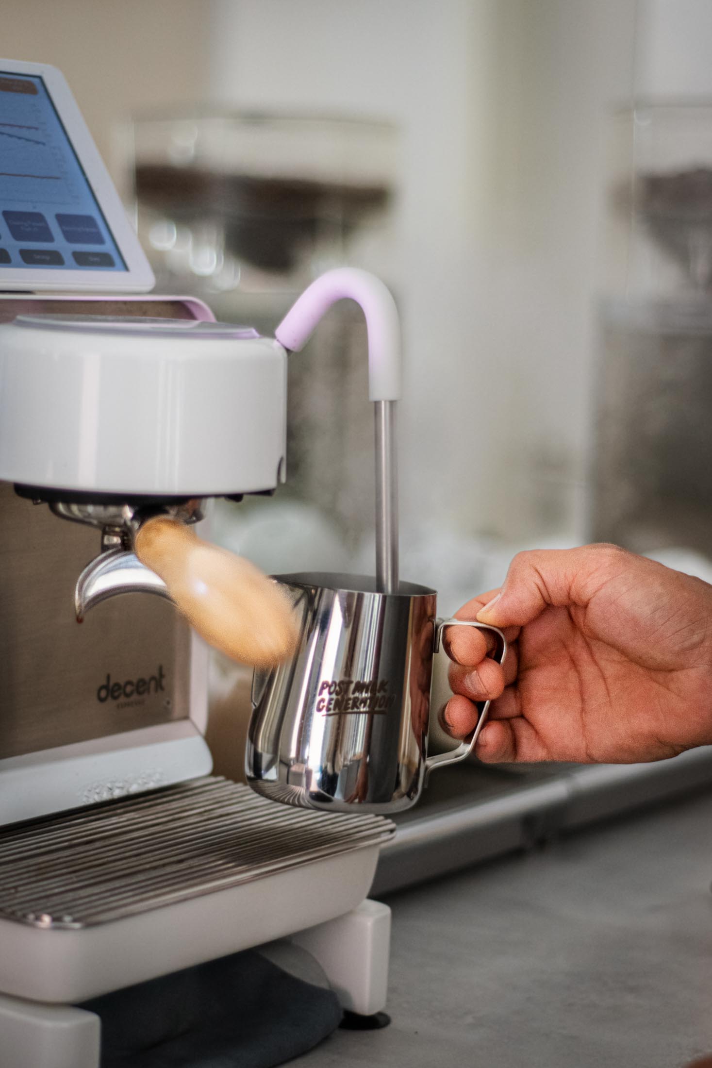 Hand schäumt Milch an einer Espressomaschine