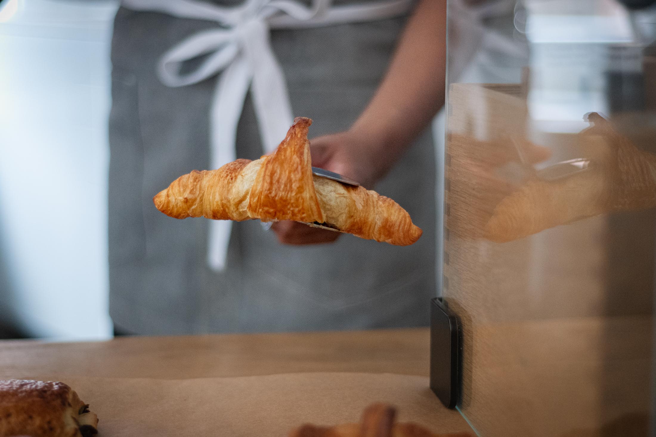 Croissant wird in die Warentheke in einem Café gelegt