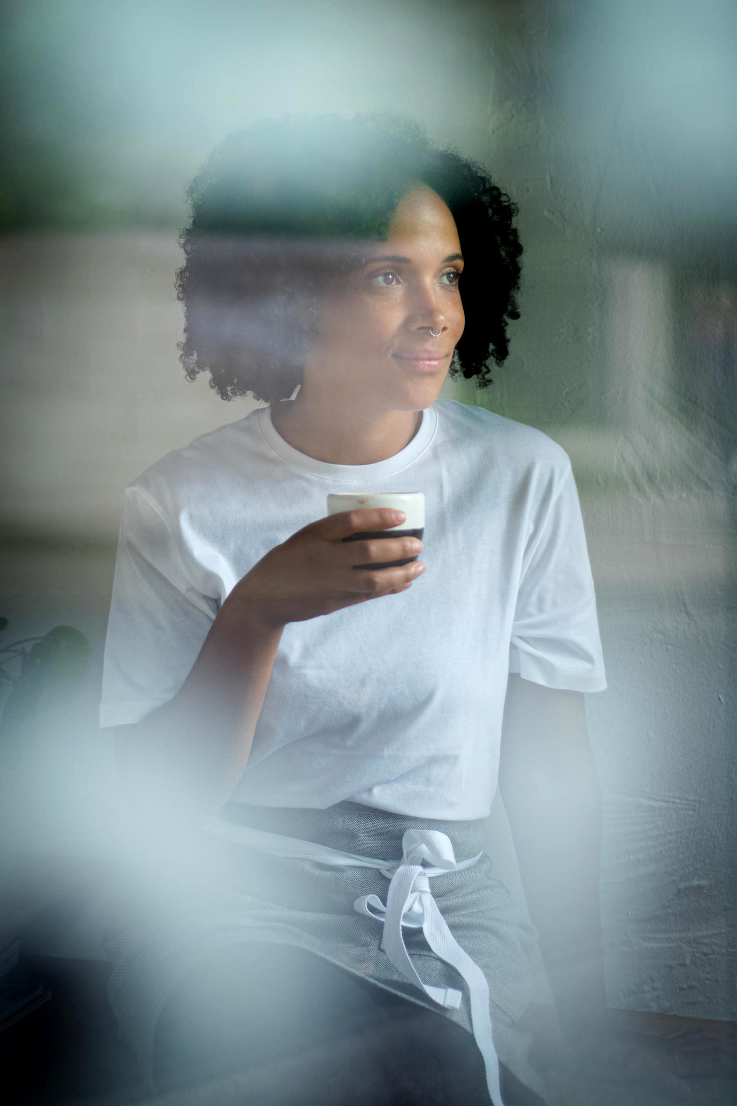 Portrait einer Frau mit Schürze durch eine Glasscheibe fotografiert