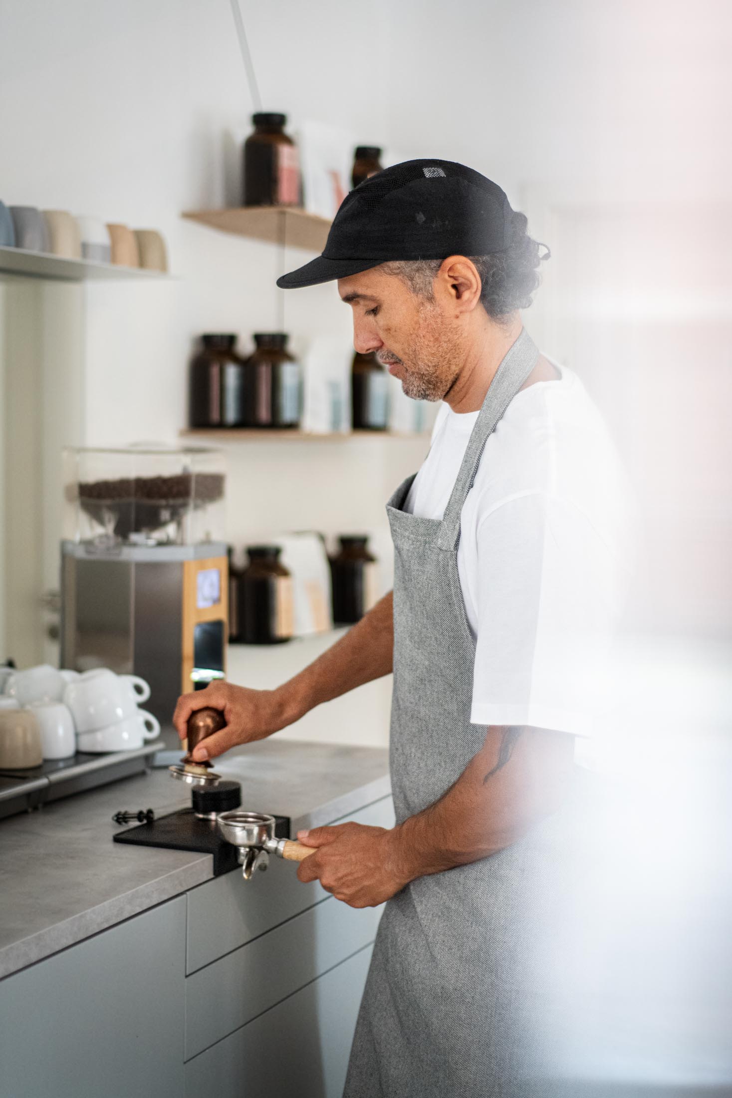 Mann in Schürze bereitet ein Getränk an einer Kaffeemaschine zu