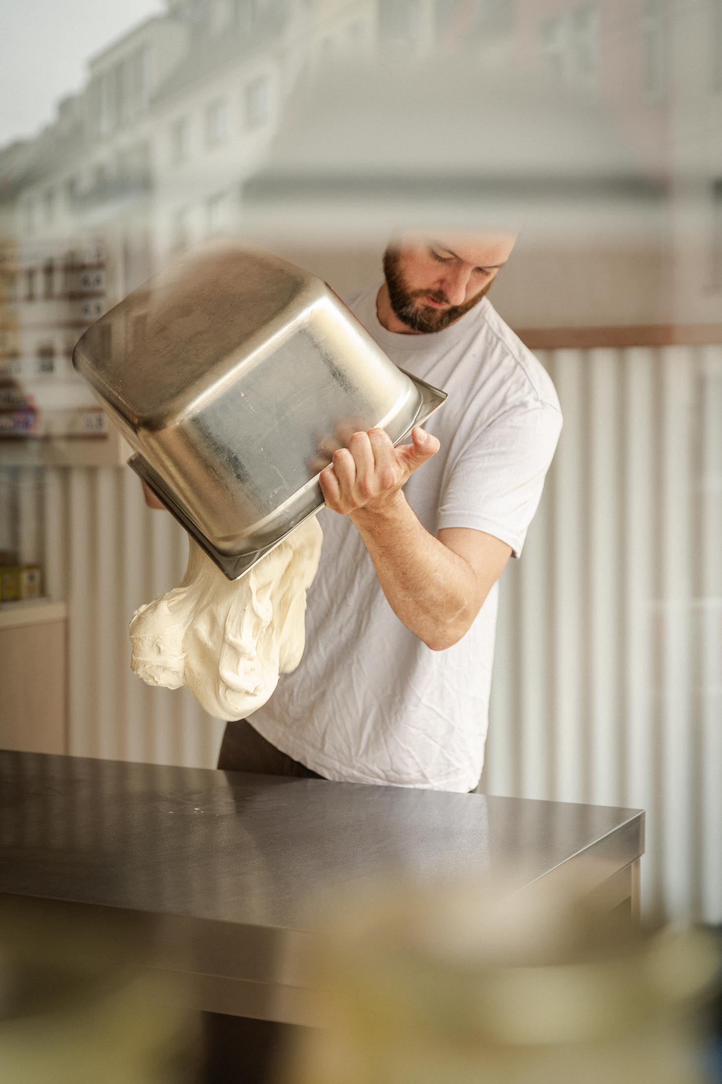 Bäcker kippt Teig aus einer Schüssel auf die Arbeitsfläche