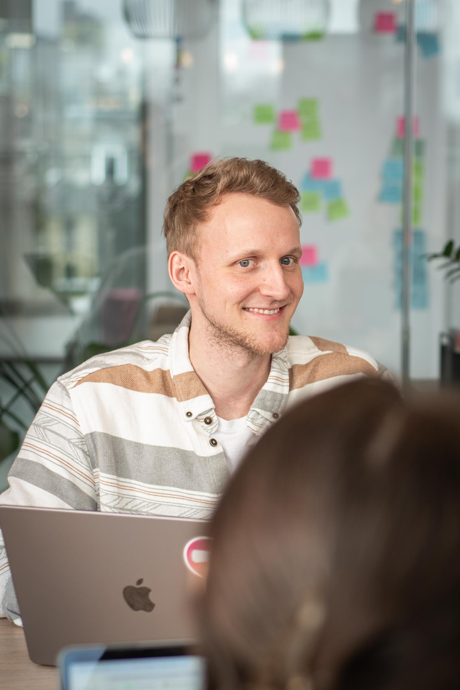 Mann mit Laptop sitzt im Meetingraum und spricht mit anderen