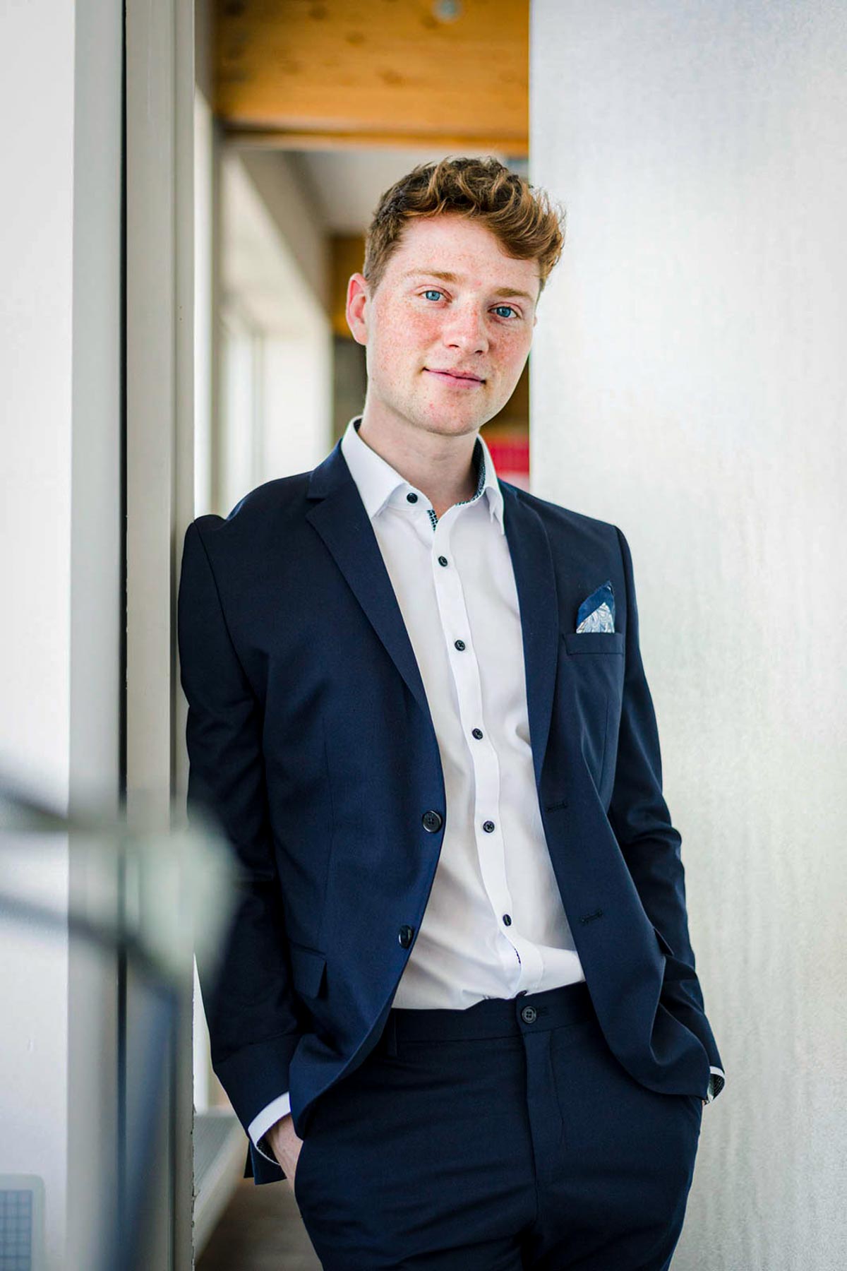 Businessportrait: Junger Mann im blauen Anzug im Flur stehend