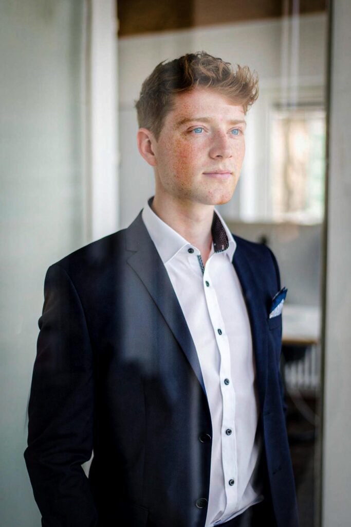 Junger Mann im Anzug am Fenster, weiches Gegenlicht